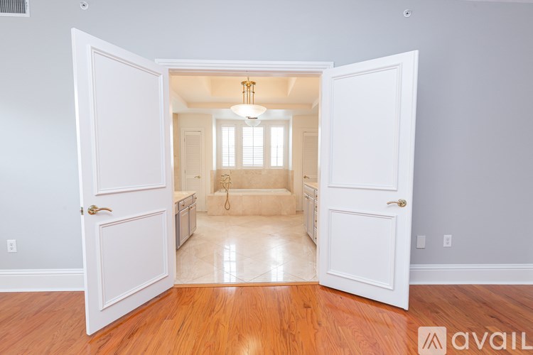A room with a wooden floor and white walls is shown through an open door.