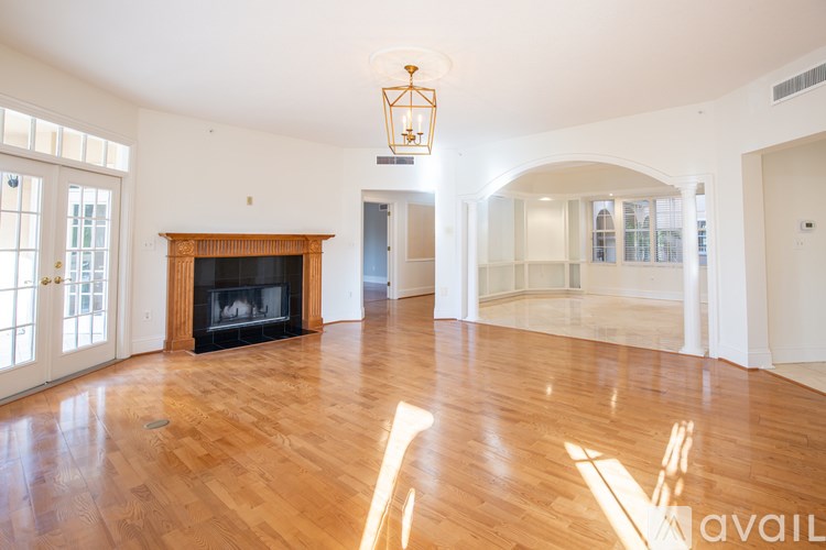 A large, empty room with a fireplace and wooden floors.