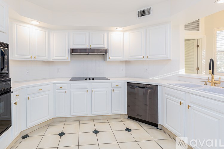 A kitchen with white cabinets and black and white tiles.