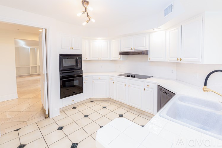 A kitchen with white cabinets and black and white tiled flooring.