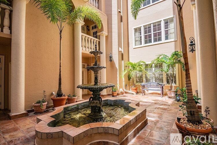 A fountain in the middle of a courtyard surrounded by potted plants.