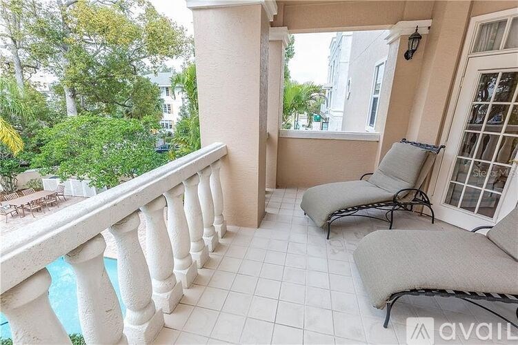 A balcony with white railings and two grey cushioned chairs.