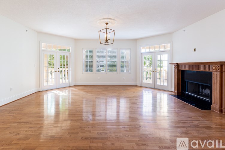 A large, empty room with wooden floors and a fireplace.