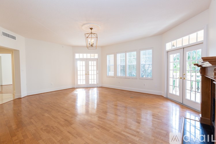 A large empty room with wooden floors and a chandelier hanging from the ceiling.