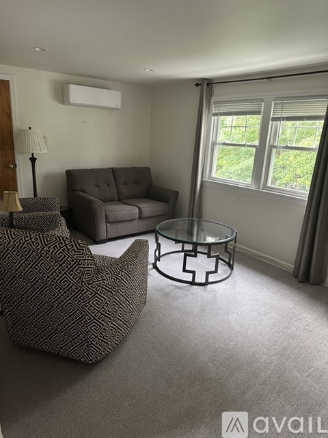 A living room with a grey couch, a glass coffee table, and a lamp.