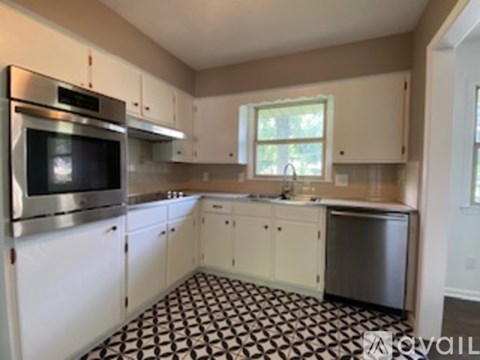 A kitchen with white cabinets and a black and white checkered floor.