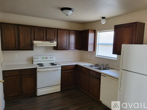 A kitchen with white appliances and wooden cabinets.