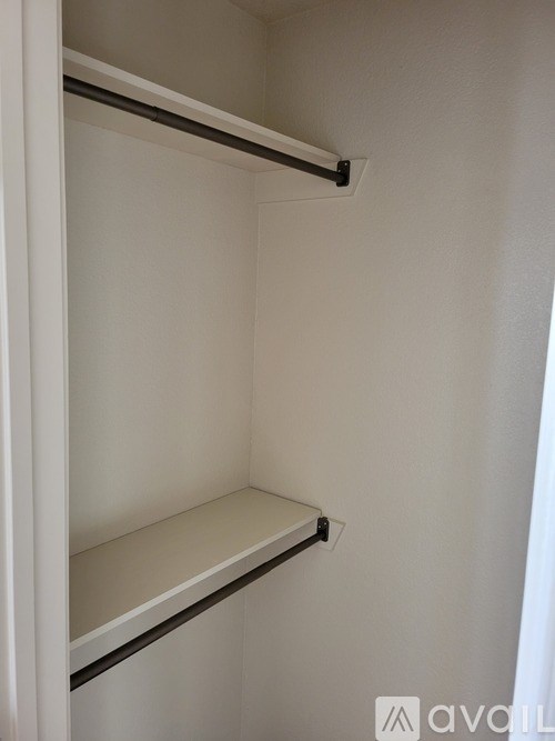 A white closet with two shelves and a hanging rail.