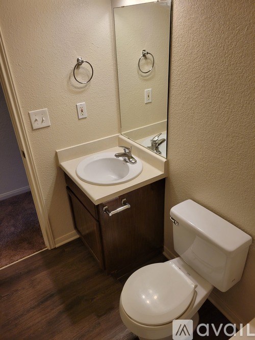 A bathroom with a toilet, sink, and mirror.