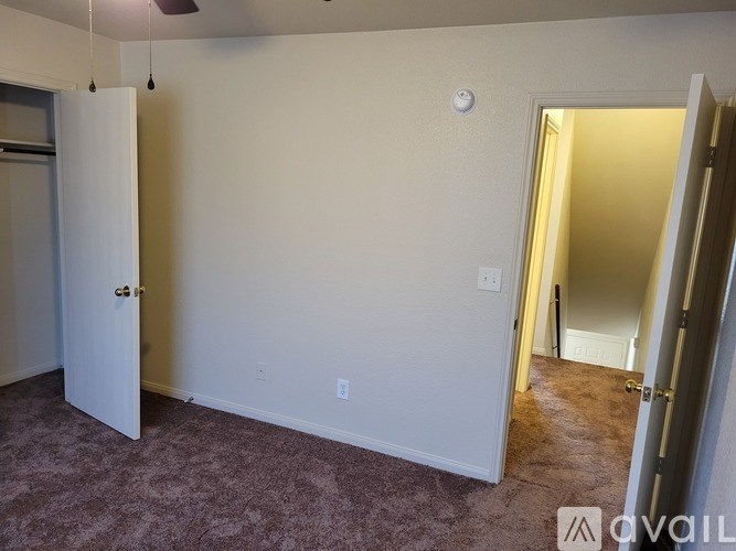 A room with a carpeted floor and a ceiling fan.