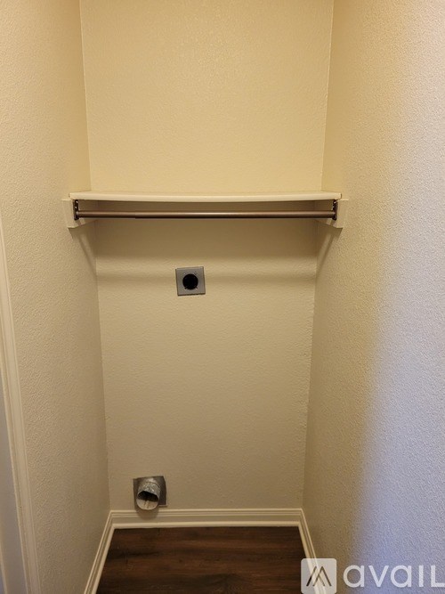 A white wall with a shelf and a vent.