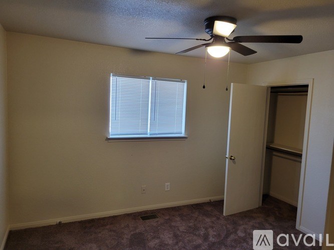 A room with a ceiling fan and a window with blinds.