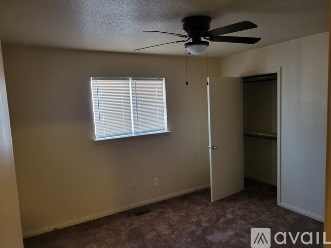 A room with a ceiling fan and a window with blinds.
