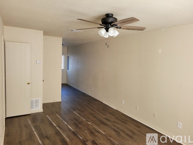 A room with a ceiling fan and wooden flooring.