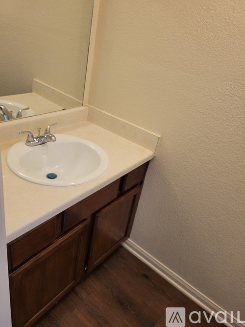 A bathroom sink with a brown cabinet and a white counter.