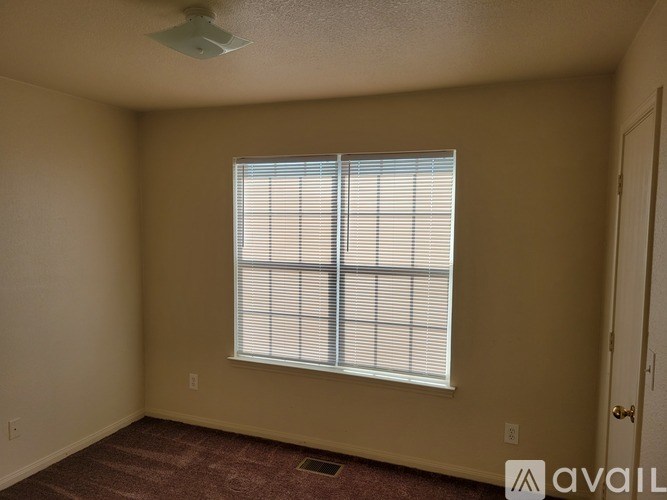 A room with a window covered in blinds and a carpet on the floor.