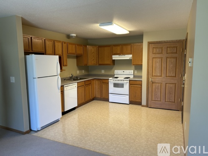 A kitchen with white appliances and wooden cabinets.