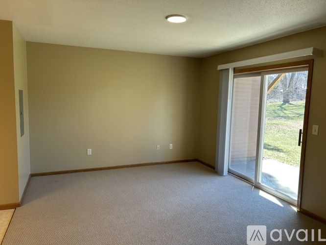 A room with a carpeted floor and a sliding glass door leading to a backyard.