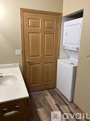 A white sink is on a counter next to a wooden door.