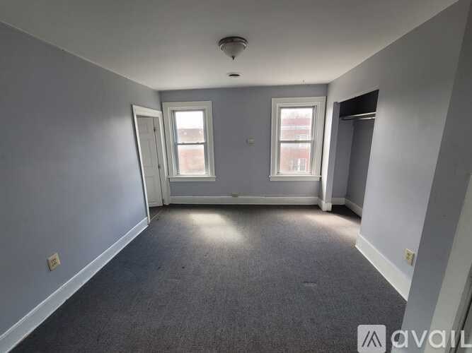 A room with grey carpet and two windows.
