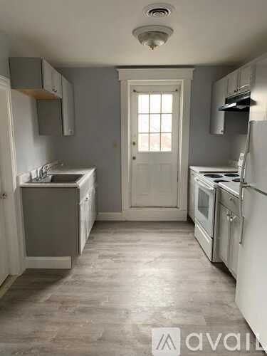 A kitchen with a white door and a window.
