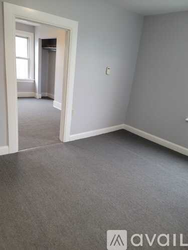 A room with a carpeted floor and a doorway leading to another room.