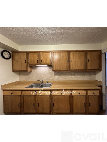 A kitchen with wooden cabinets and a clock on the wall.