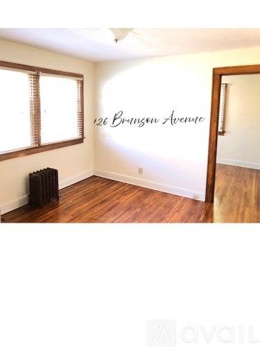 A room with a wood floor and a wall that says 126 Brungo Avenue.