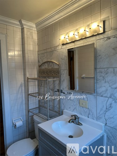 A bathroom with a marble wall and a white toilet.
