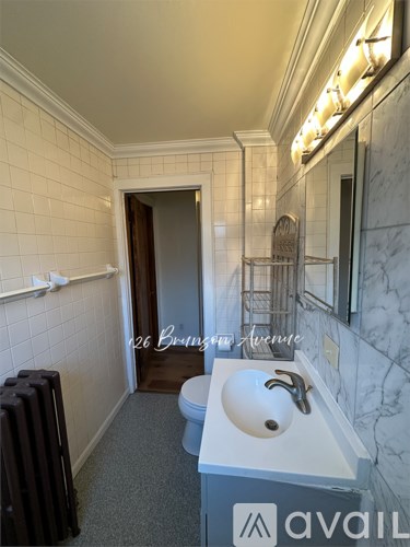 A bathroom with a toilet, sink, and mirror.