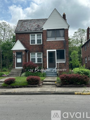 A brick house with a white roof and a sign that says 26 Brigham Avenue.