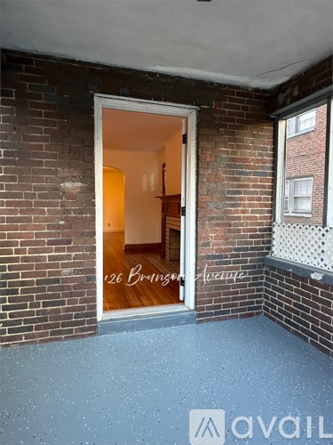 A room with a brick wall and a doorway leading to another room.