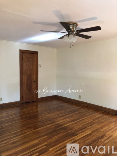 A room with a ceiling fan and wooden flooring.