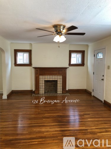 A living room with a fireplace and a ceiling fan.