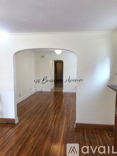 A room with wood flooring and a doorway leading to another room.