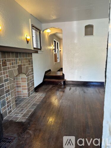 A hallway with a brick fireplace and wooden floors.