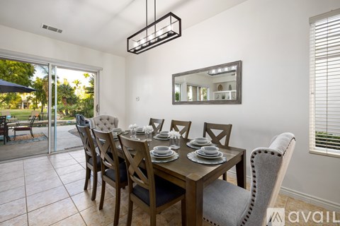 A dining room with a table set for six with a view of the backyard.