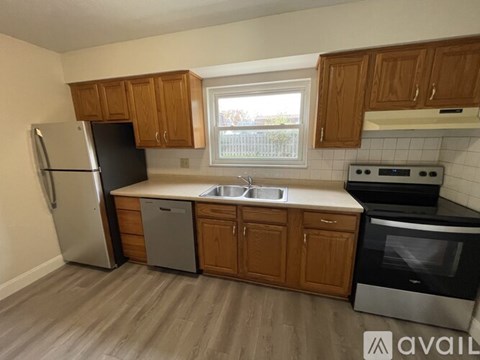 A kitchen with wooden cabinets and a stainless steel refrigerator.