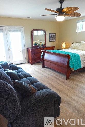 A bedroom with a bed, dresser, mirror, and a ceiling fan.