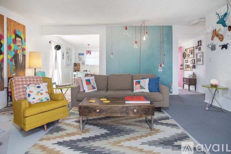 A living room with a yellow chair, a brown couch, and a rug.