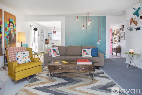A living room with a yellow chair, a brown couch, and a rug.