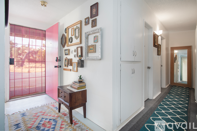 A hallway with a rug and pictures on the wall.
