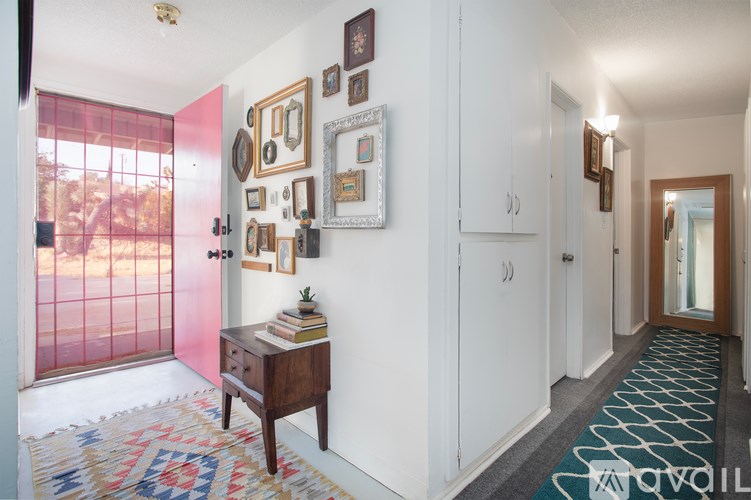 A hallway with a rug and pictures on the wall.