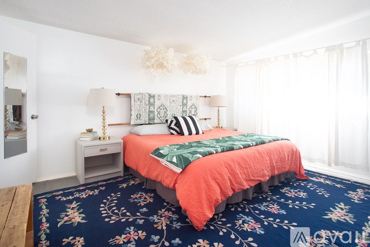 A bedroom with a bed, nightstand, and lamp.