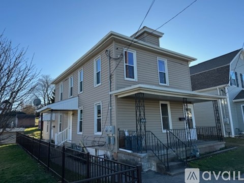 A two-story house with a black fence in front.