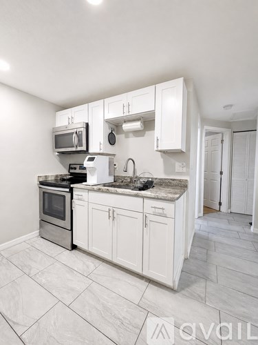 A kitchen with a black fridge, white cabinets, and a granite countertop.