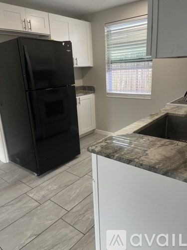 A black refrigerator in a kitchen with a marble counter.