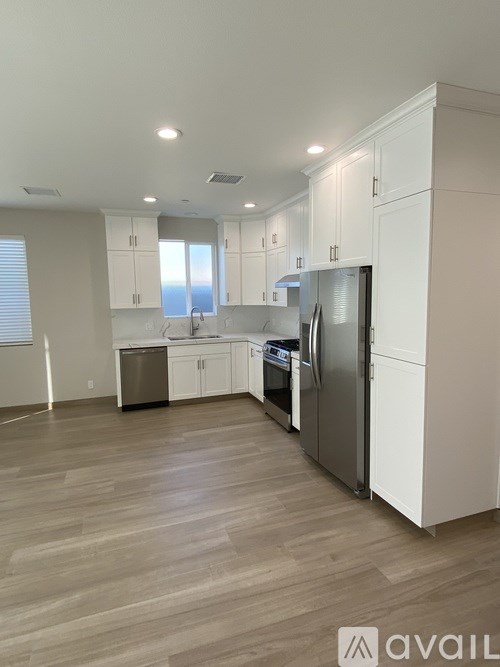A kitchen with white cabinets and a wooden floor.