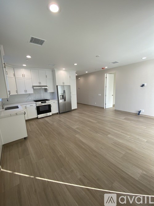 A spacious kitchen with white appliances and wooden flooring.