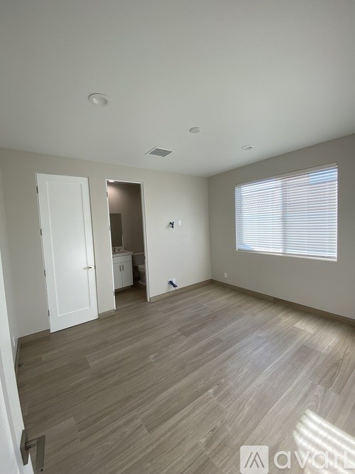 A room with wooden flooring and a window with blinds.